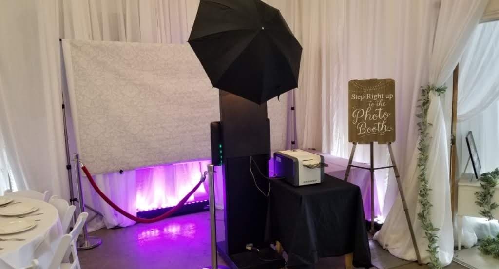 Photo booth setup with backdrop, lighting, and welcome sign